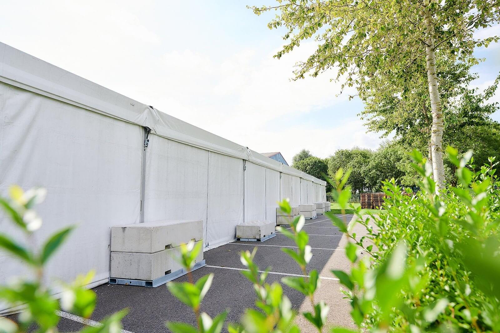 Zijkant tenthal Bax Music met betonblokken als verankering