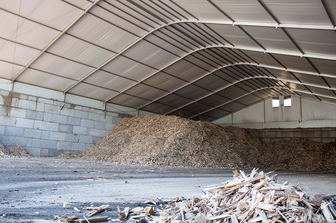 Berg met houtsnippers en houtafval droog opgeslagen onder overkapping Bio Dry BV