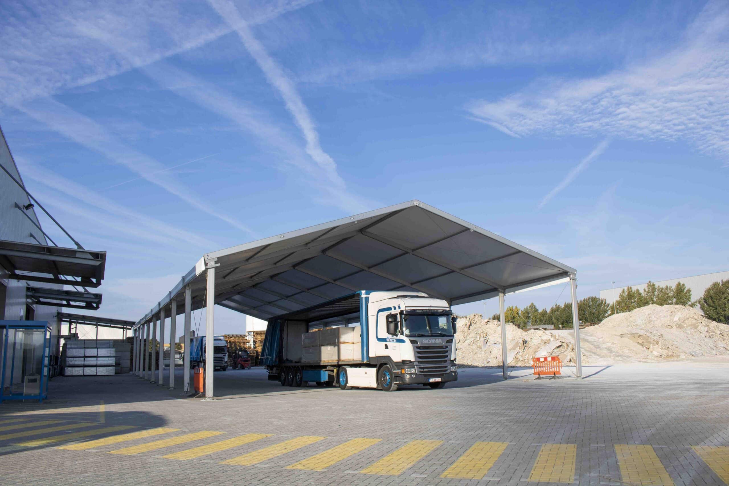 Vrachtwagen onder industriële overkapping bij Knauf