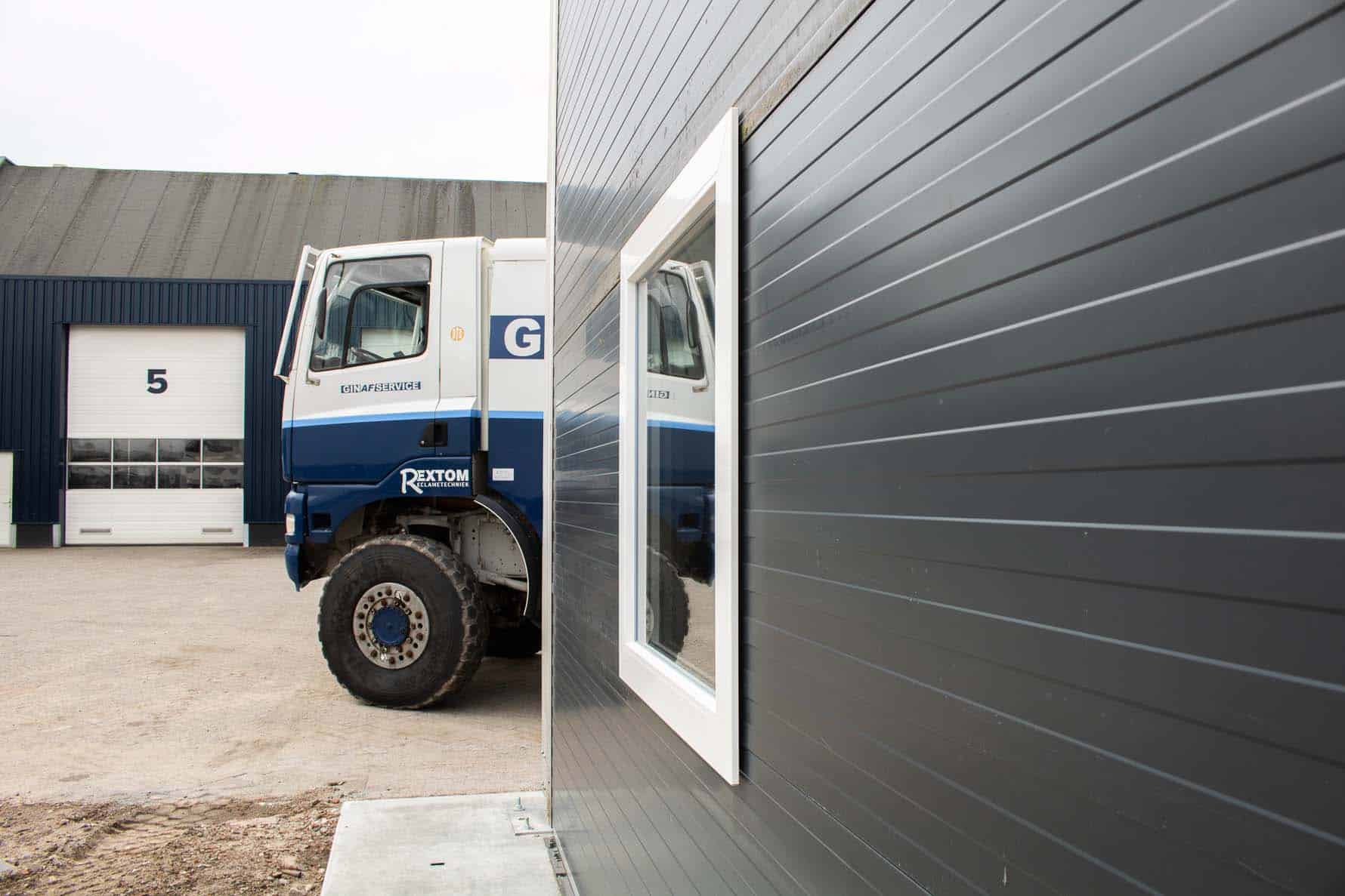 Van Ginkel Trucks achter tenthal met raam