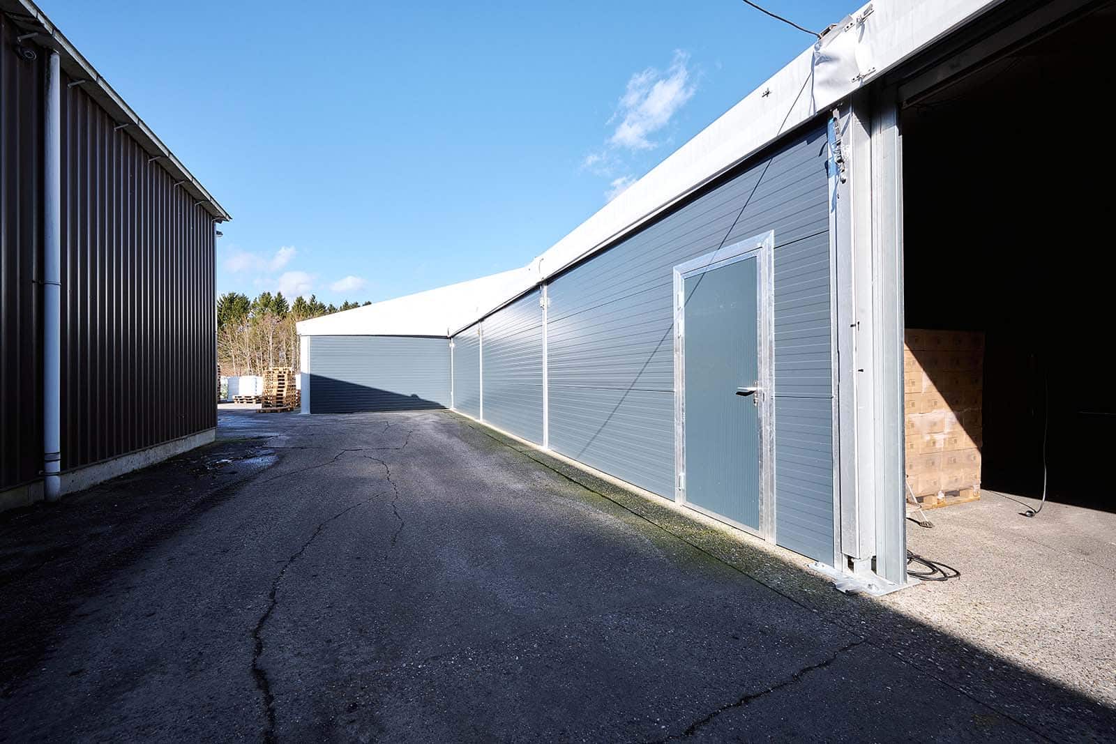 Buitenzijde tenthal Seasons Products met elektrische roldeur met loopdeur