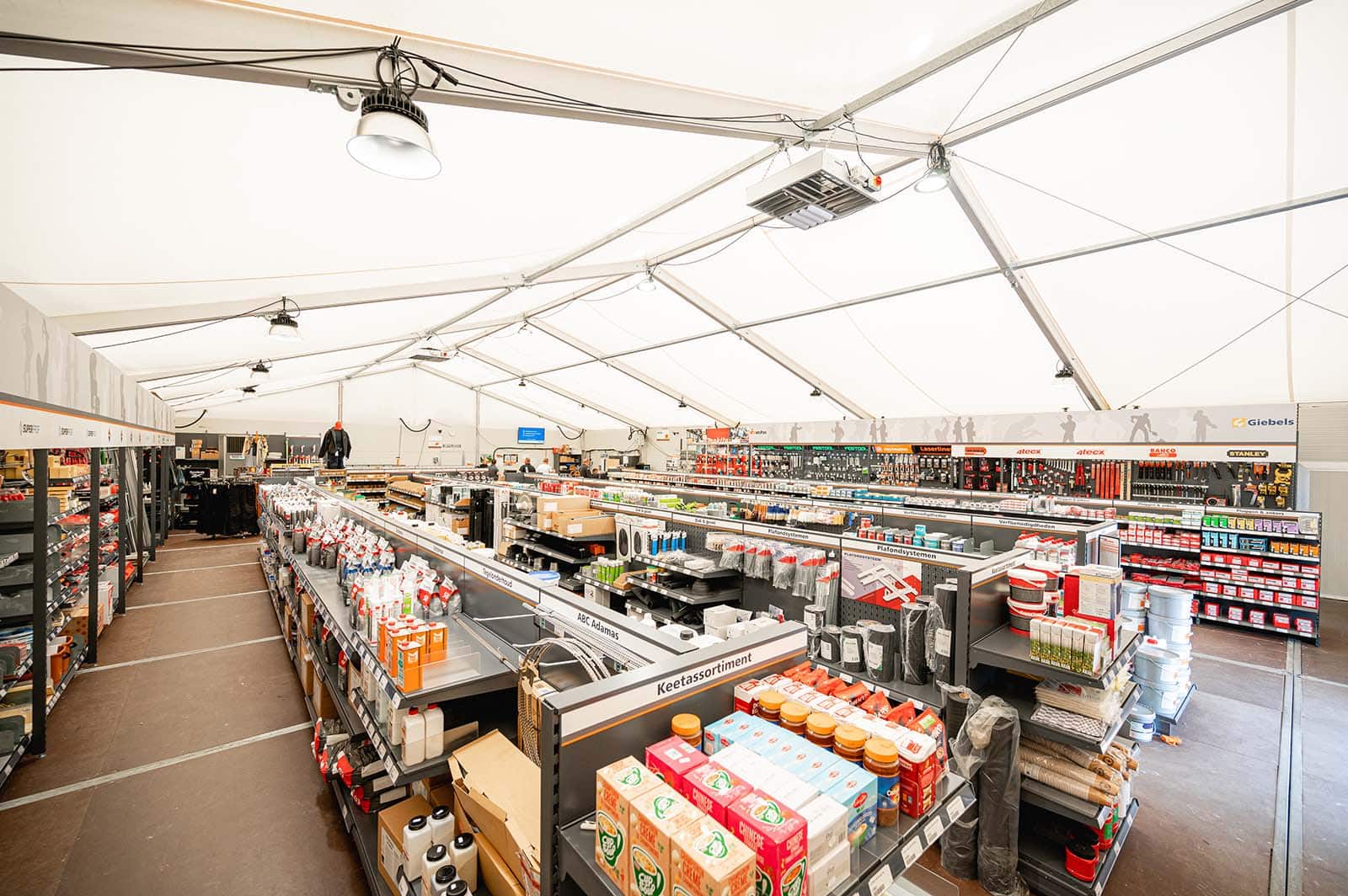 Een tijdelijke winkelruimte met stellingen met producten van Hoek wegenbouw