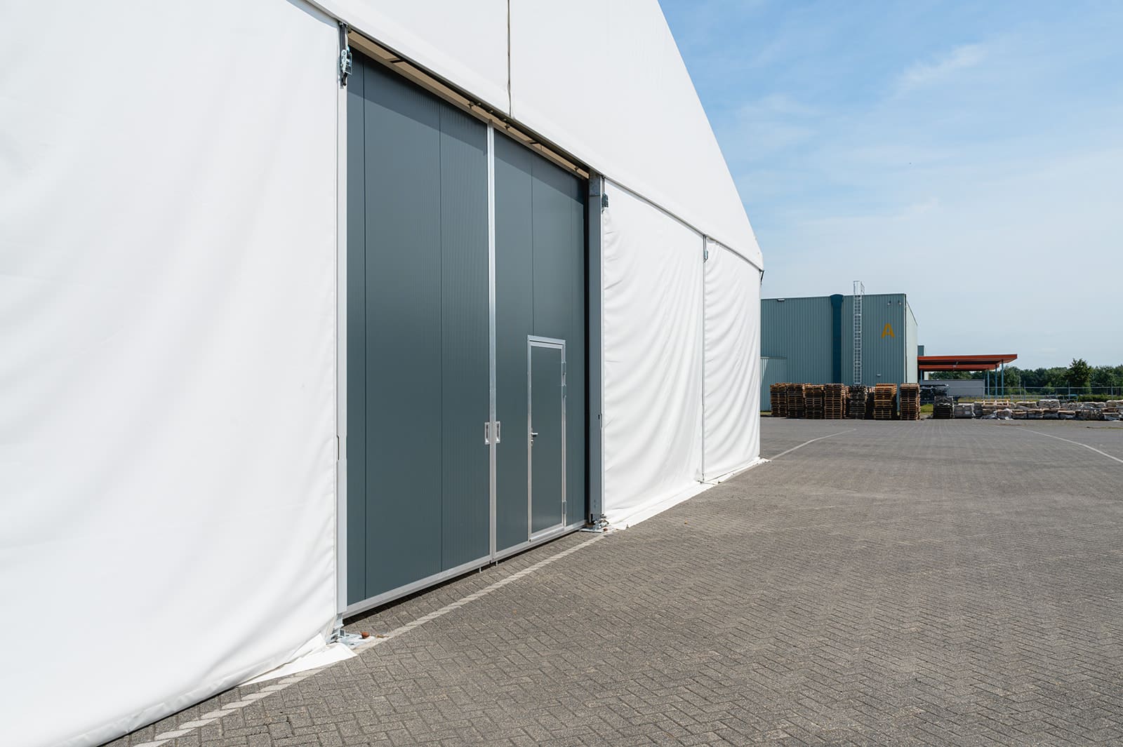 Handmatige schuifdeur met loopdeur in ongeïsoleerde tenthal voor HUSA Logistics
