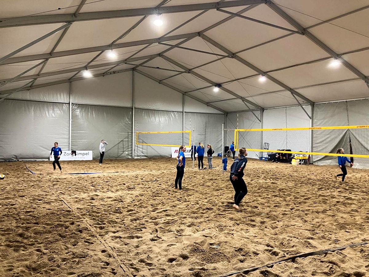 Mensen aan het volleyballen in een tijdelijke sporthal